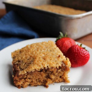 Piece of oatmeal cake with broiled coconut topping on plate, ready to eat.