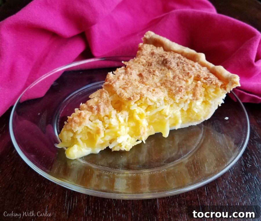 A detailed shot of a slice of pineapple coconut pie, highlighting the vibrant yellow filling and golden crust.