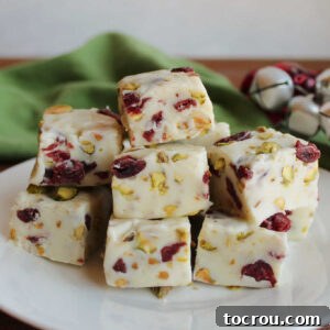 Plate of creamy vanilla fudge with dried cranberries and pistachio pieces inside.