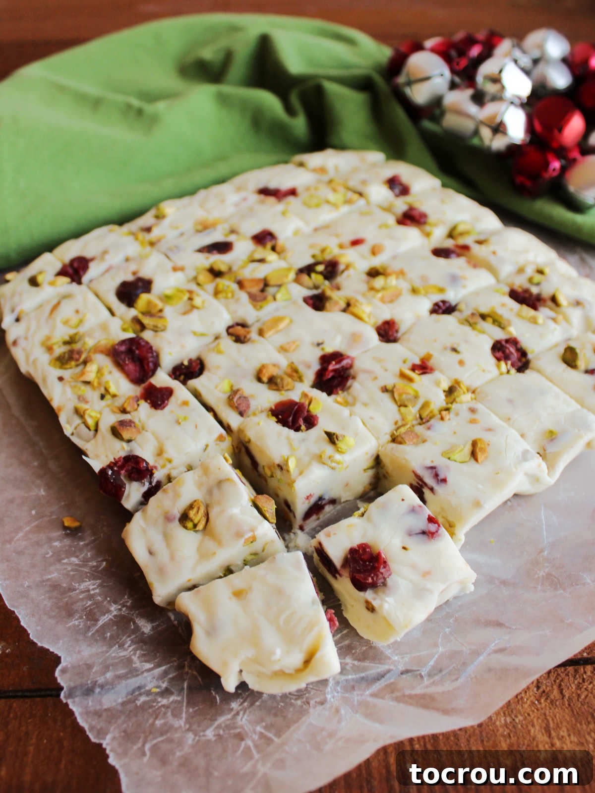 Square of vanilla fudge with cranberries and pistachios after it has been set and cut into cubes. 