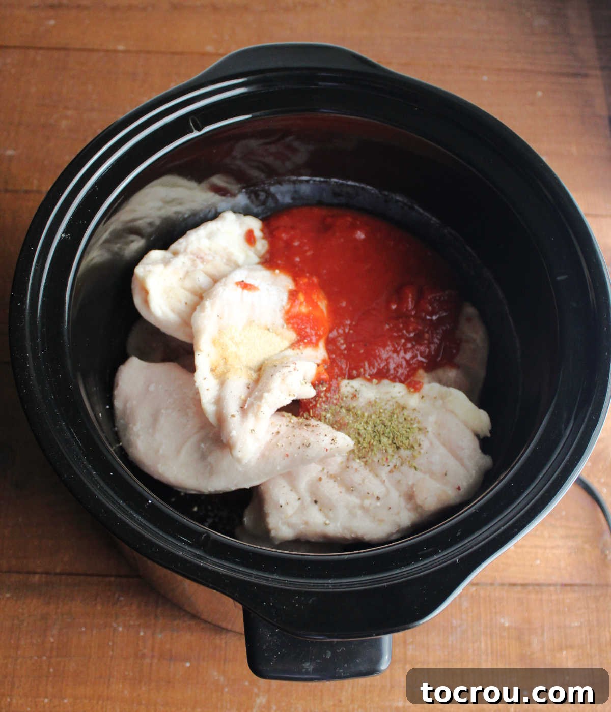 Simple ingredients for your slow cooker chicken parmesan. Chicken, marinara sauce, garlic powder, and dry oregano ready for the crockpot.
