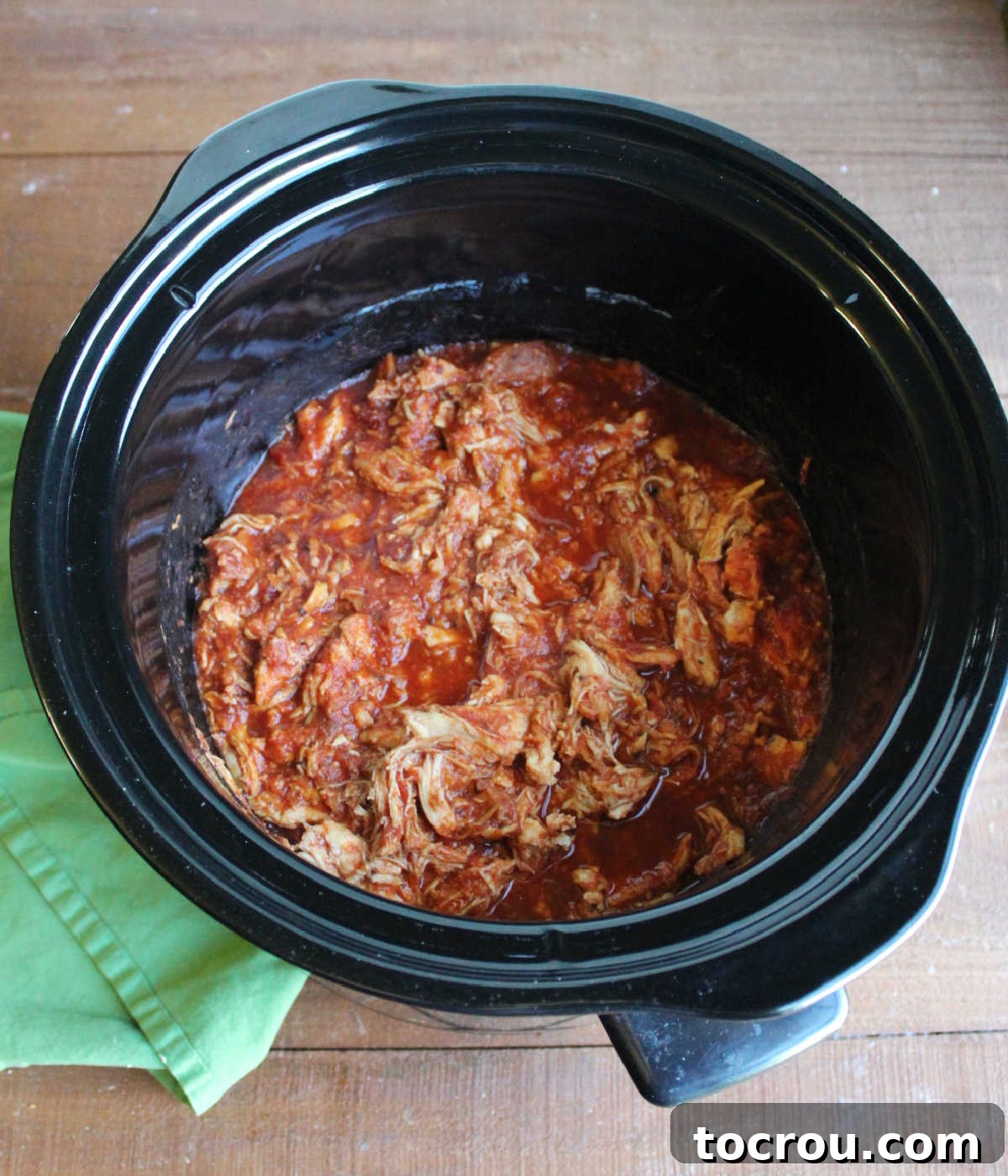 Tender shredded chicken parmesan filling after slow cooking. Shredded chicken and marinara in a slow cooker, perfectly cooked and ready for assembly.