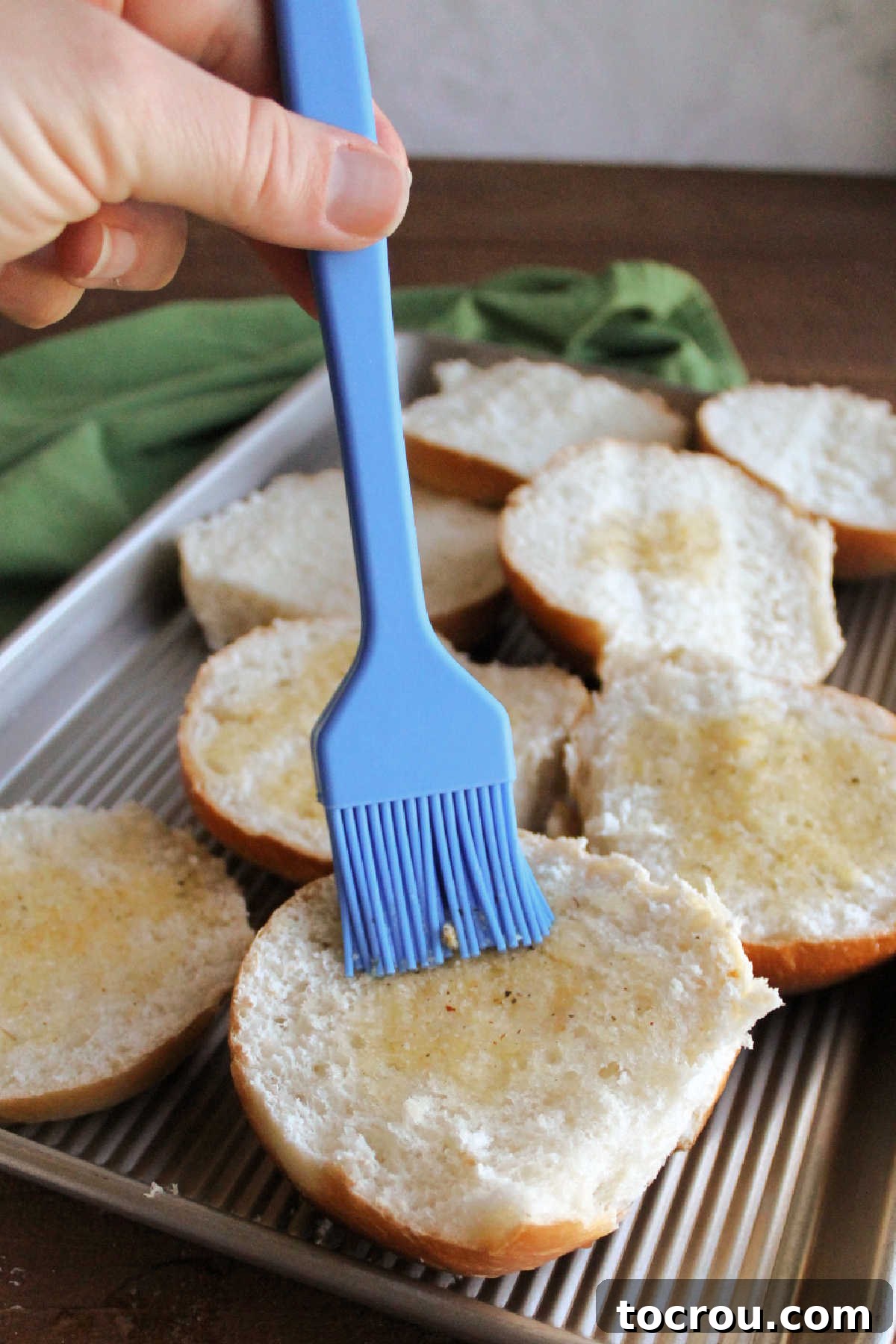 Prepare your buns for the ultimate garlic bread experience. Brushing garlic butter on hamburger buns before toasting.