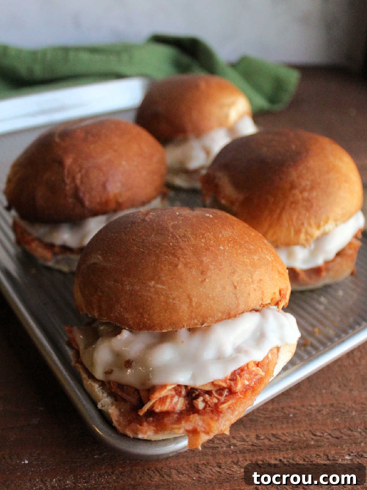 The perfect Crockpot Chicken Parmesan Sandwich ready to enjoy. Close-up of shredded chicken parmesan sandwiches with melted cheese on toasted garlic bread buns.