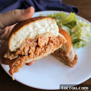 Inside of shredded chicken parm sandwich with melted provolone cheese and toasted garlic bread bun.