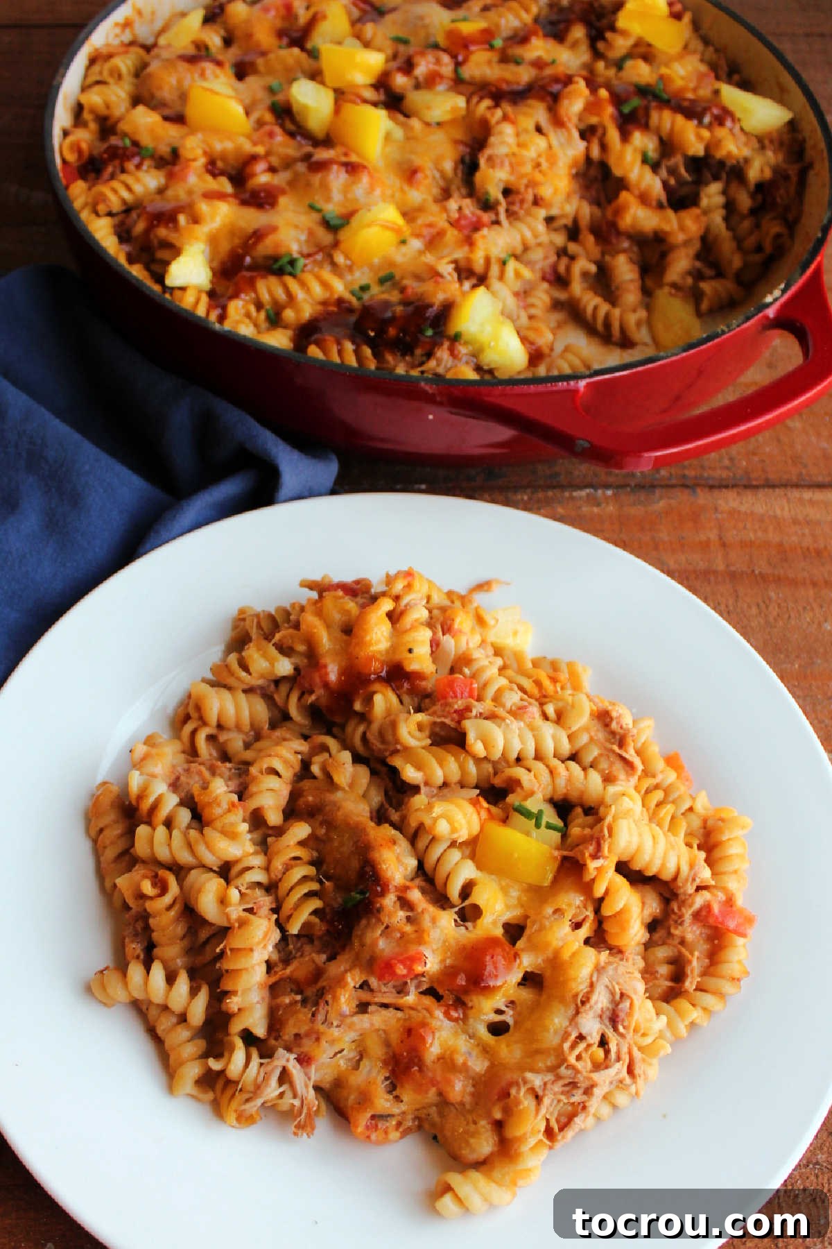 Velvety BBQ Pulled Pork Pasta 8 Plate of rotini pasta and pulled pork coated with creamy bbq sauce and melted cheese, ready to eat.