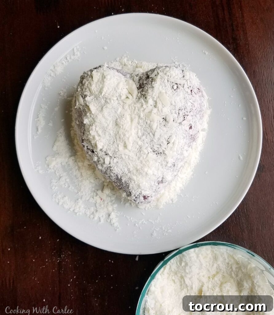 Red Velvet Cheesecake Ball 3 covering red velvet cheese ball in white chocolate shavings,