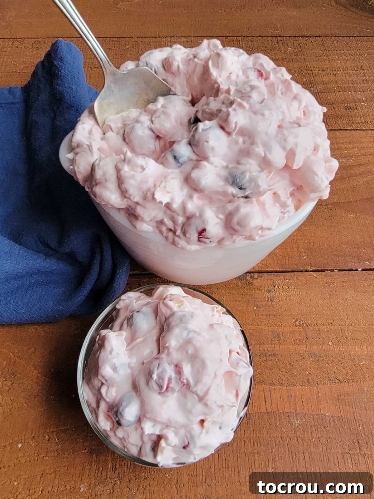 Looking down on a serving bowl piled high with pink fluff junk yard salad next to a small bowl with a serving of the fluff salad inside. 