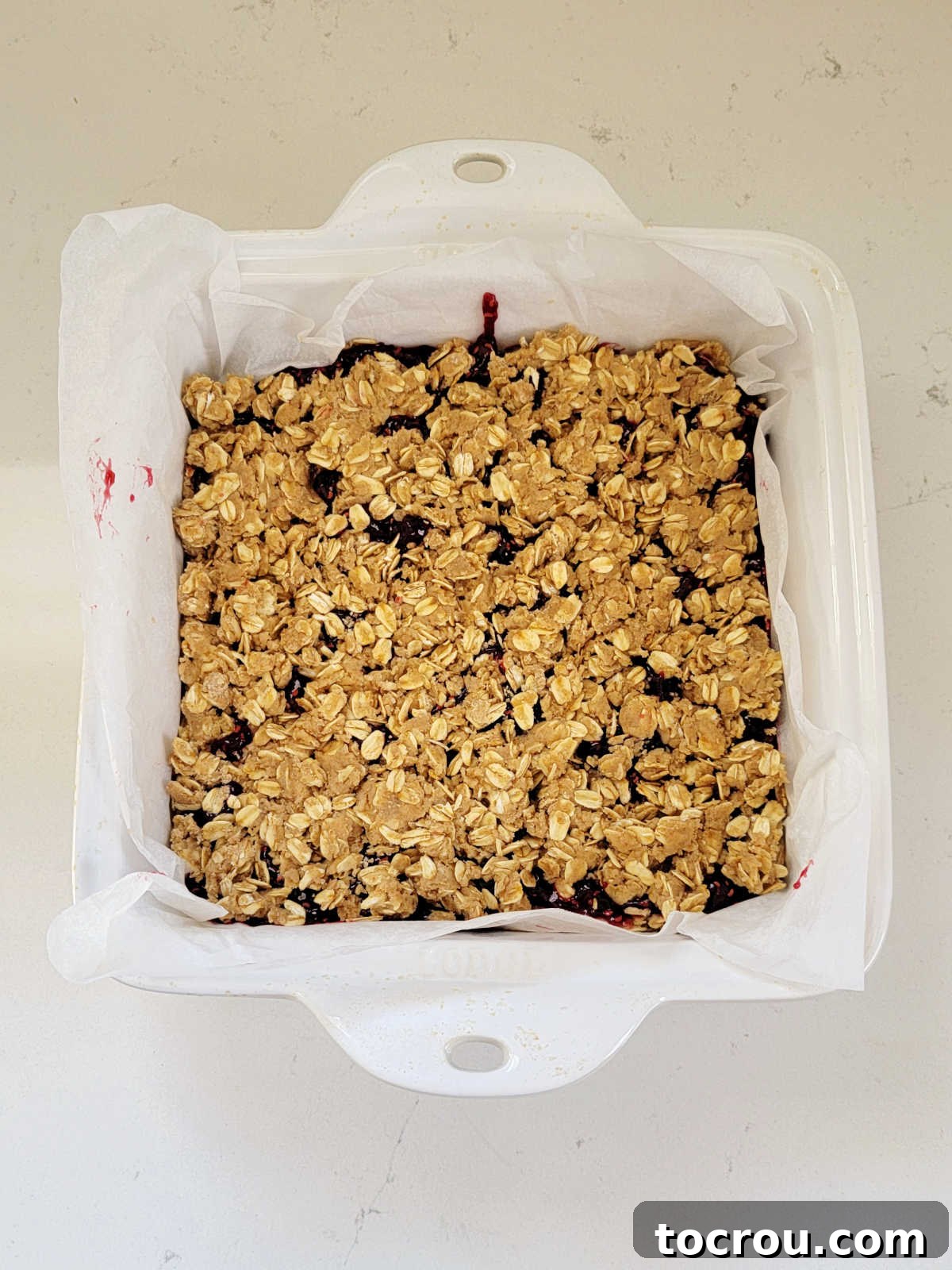 Sourdough breakfast bars in a parchment-lined square baking dish, ready to be baked to golden perfection.