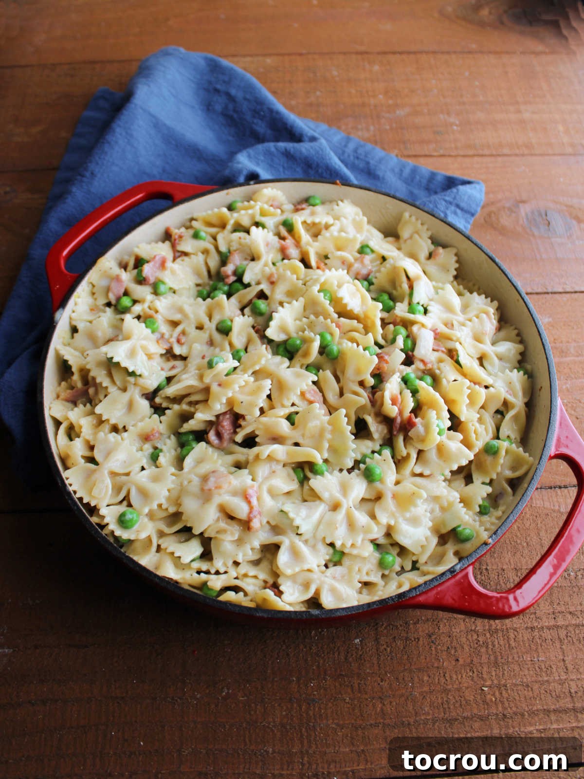 Mixing Pasta and Alfredo Sauce Cooked farfalle pasta and alfredo sauce mixed into peas, bacon and onion mixture.