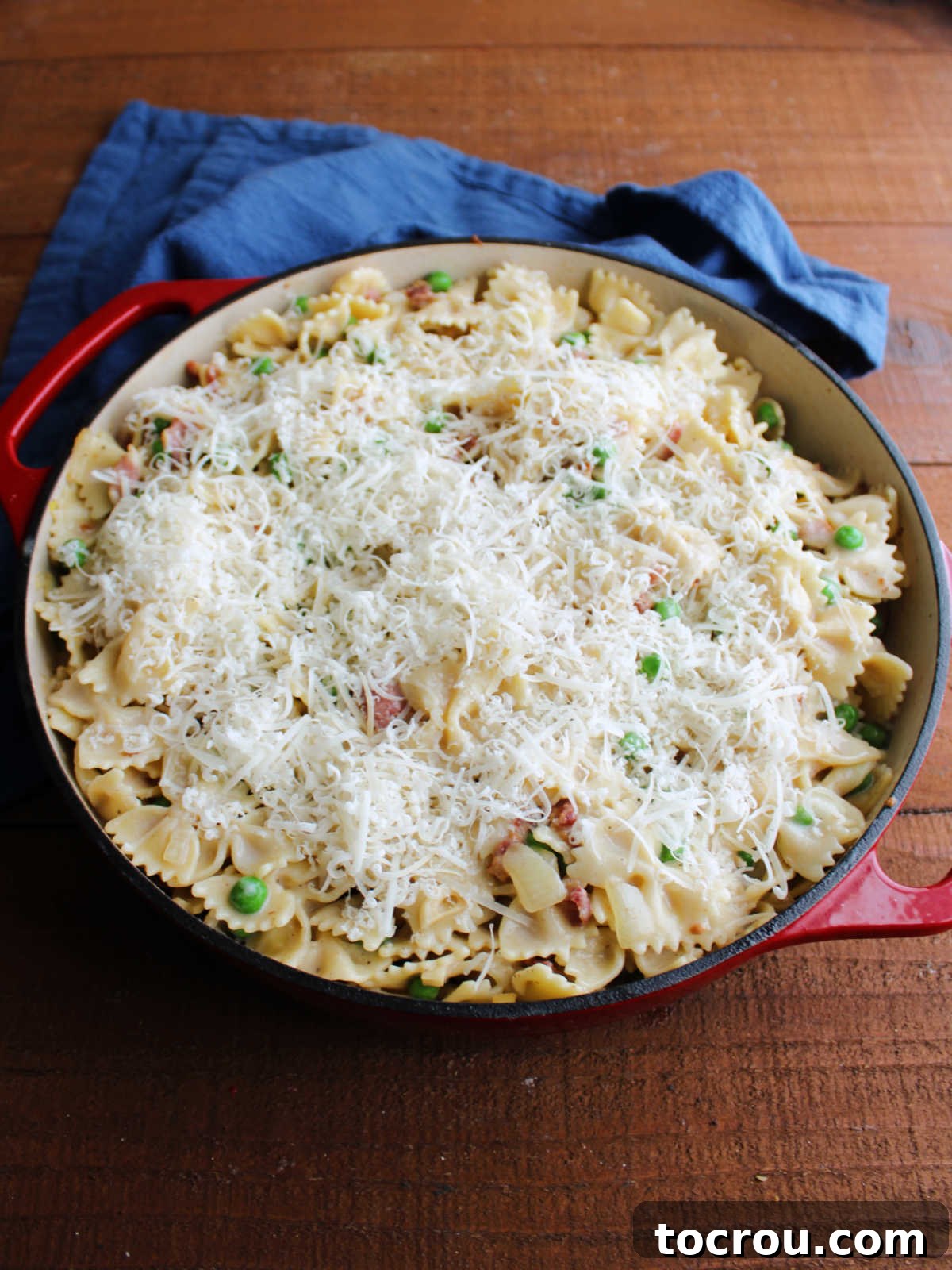 Parmesan Topping for Baking Freshly grated parmesan cheese sprinkled over alfredo pasta mixture in pan, ready to go in the oven.