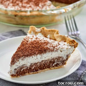 A perfectly portioned slice of homemade French silk pie with its rich, solid chocolate filling, topped generously with fluffy whipped cream and elegant chocolate shavings, presented invitingly.