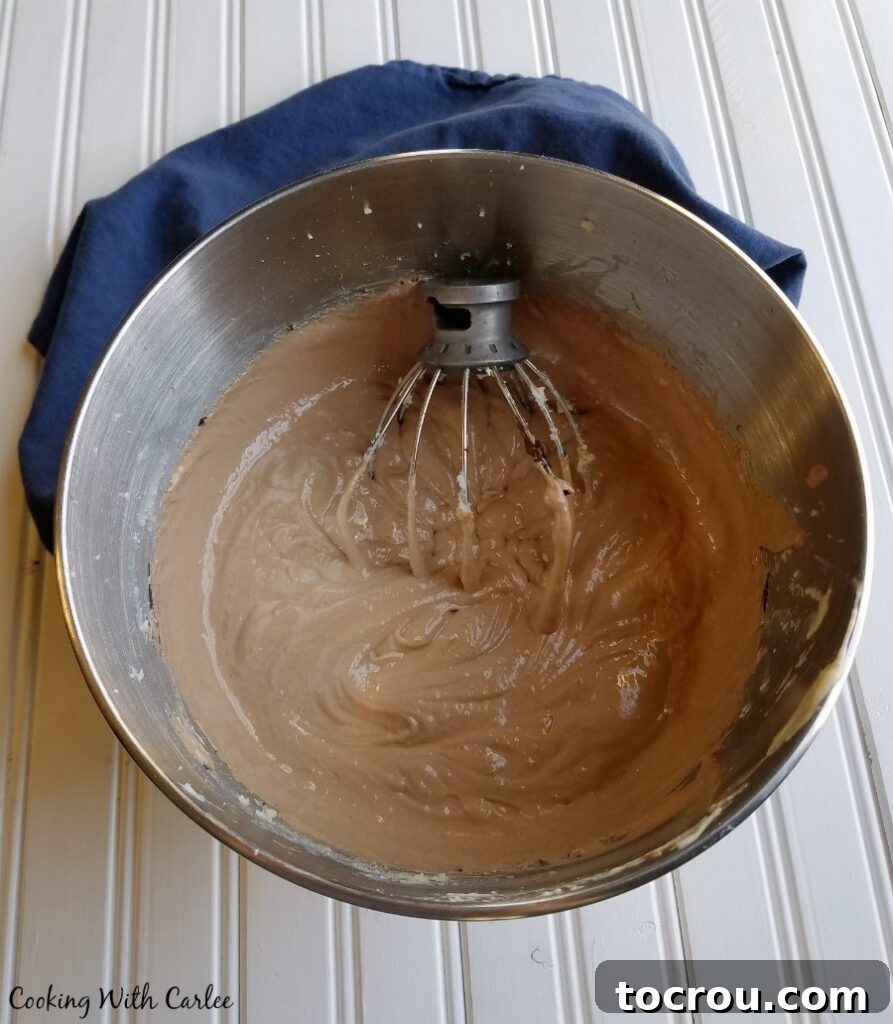 The finished, glossy, and irresistibly creamy chocolate pie filling gracefully presented inside a stand mixer bowl, perfectly aerated and exquisitely smooth, poised for its final transfer into the prepared pie crust.
