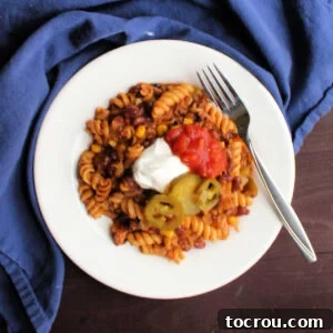 Dinner plate filled with helping of taco pasta with sour cream and jalapenos.