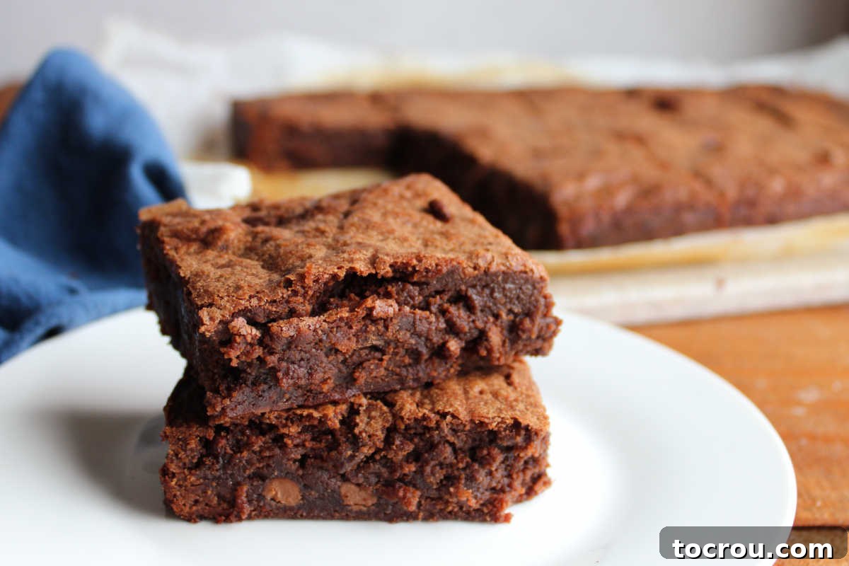 Two sourdough brownies stacked on top of each other with the remaining brownies in the background.