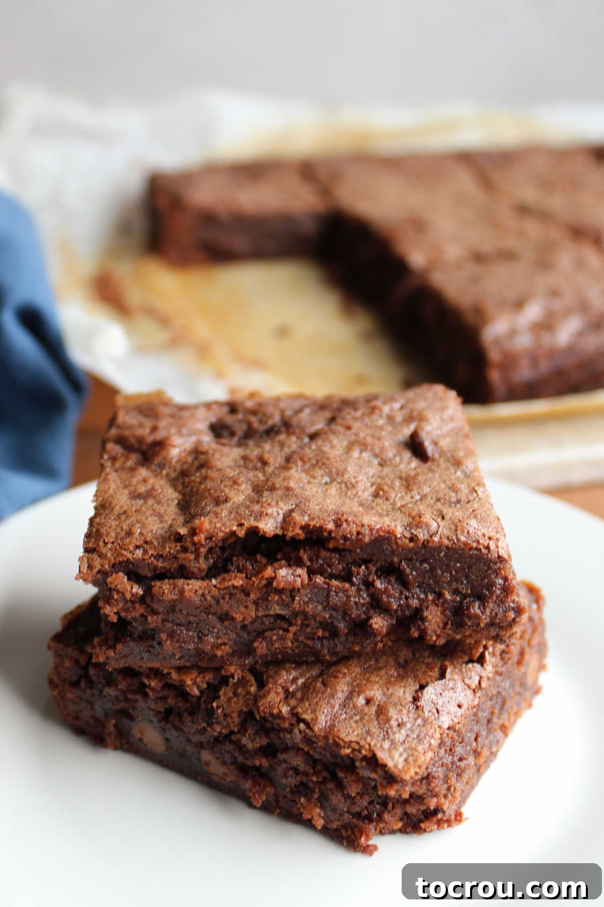 Two sourdough brownies stacked on top of each other with the remaining brownies in the background.