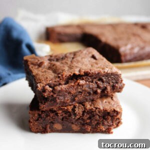 Two sourdough brownies stacked on top of each other with the remaining brownies in the background.