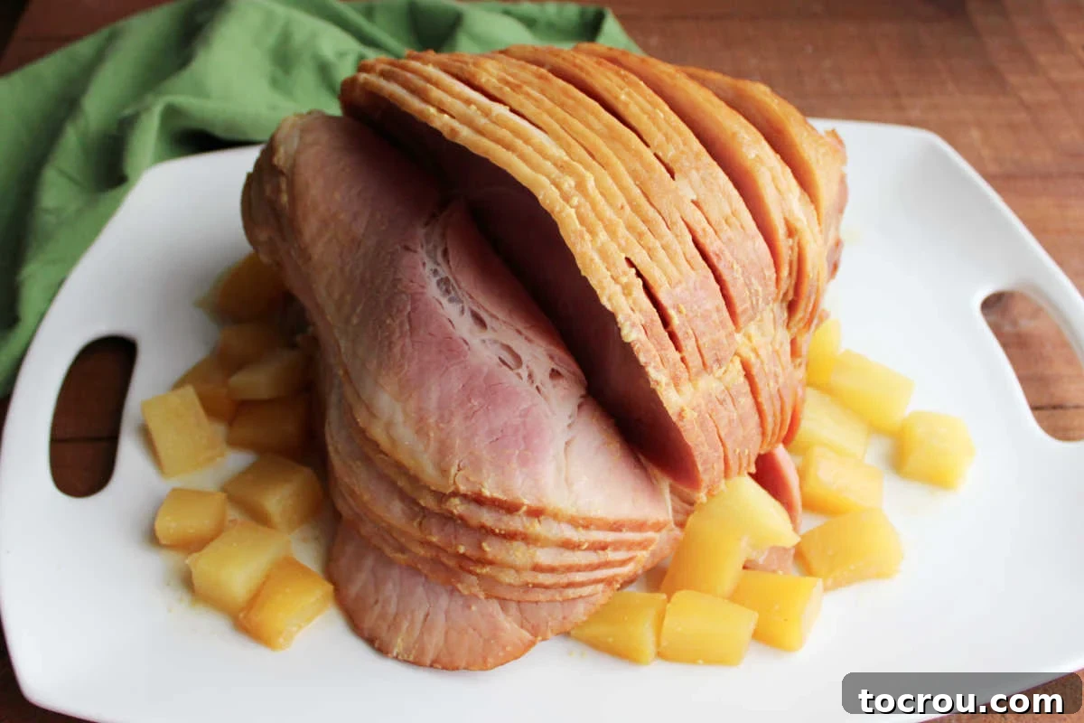 Golden Pineapple Glazed Slow Cooker Ham 2 Platter with spiral ham that was cooked in crockpot with mustard, brown sugar, and pineapple chunks, ready to serve.