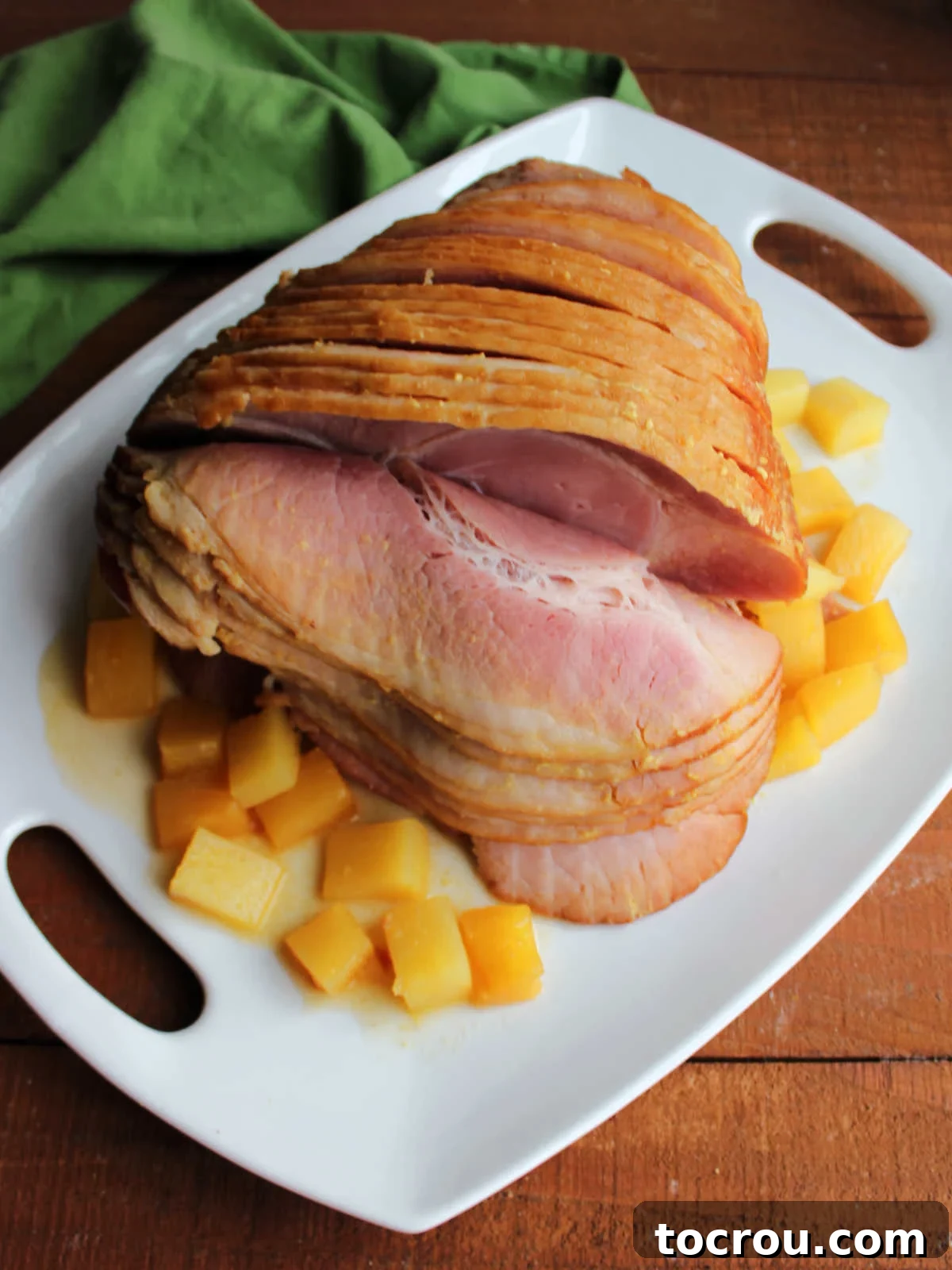 Golden Pineapple Glazed Slow Cooker Ham 5 Platter with cooked spiral ham and chunks of pineapple, ready to be served.