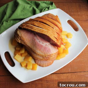 Platter with cooked spiral ham and chunks of pineapple, ready to be served.