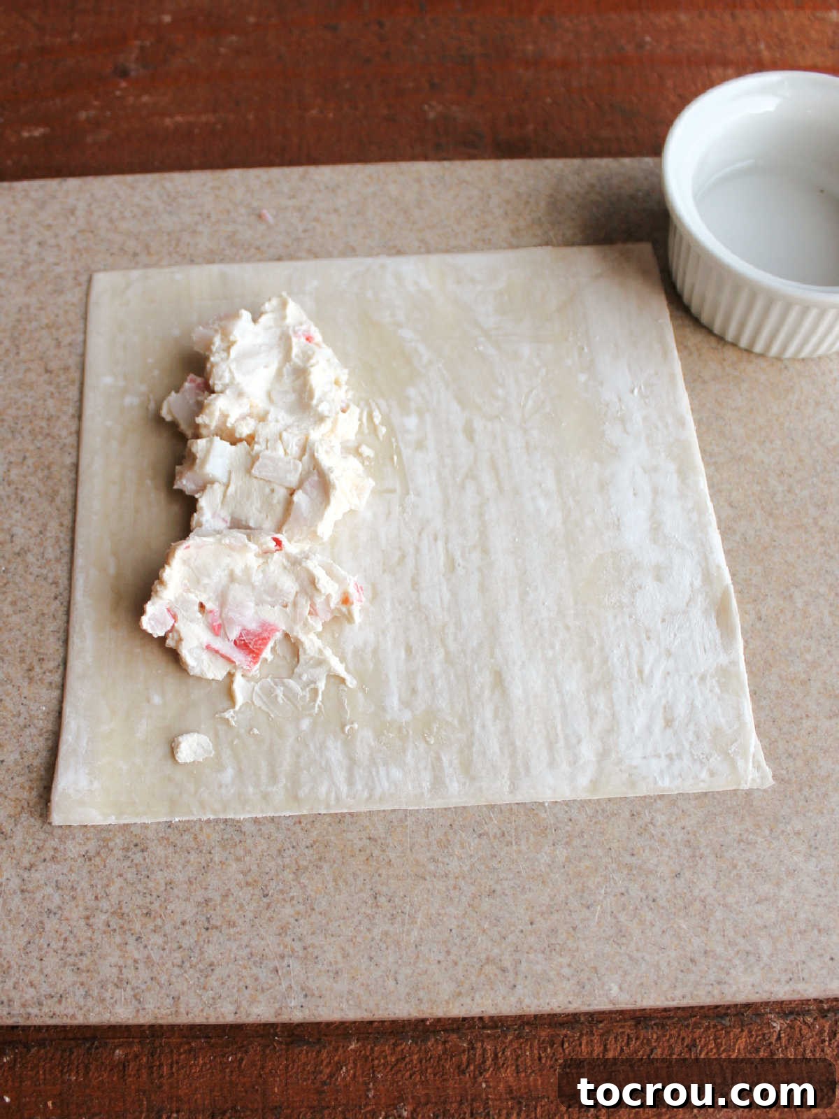 Filling an Egg Roll Wrapper Two tablespoons of the creamy crab rangoon filling placed neatly on an egg roll wrapper, ready for folding.