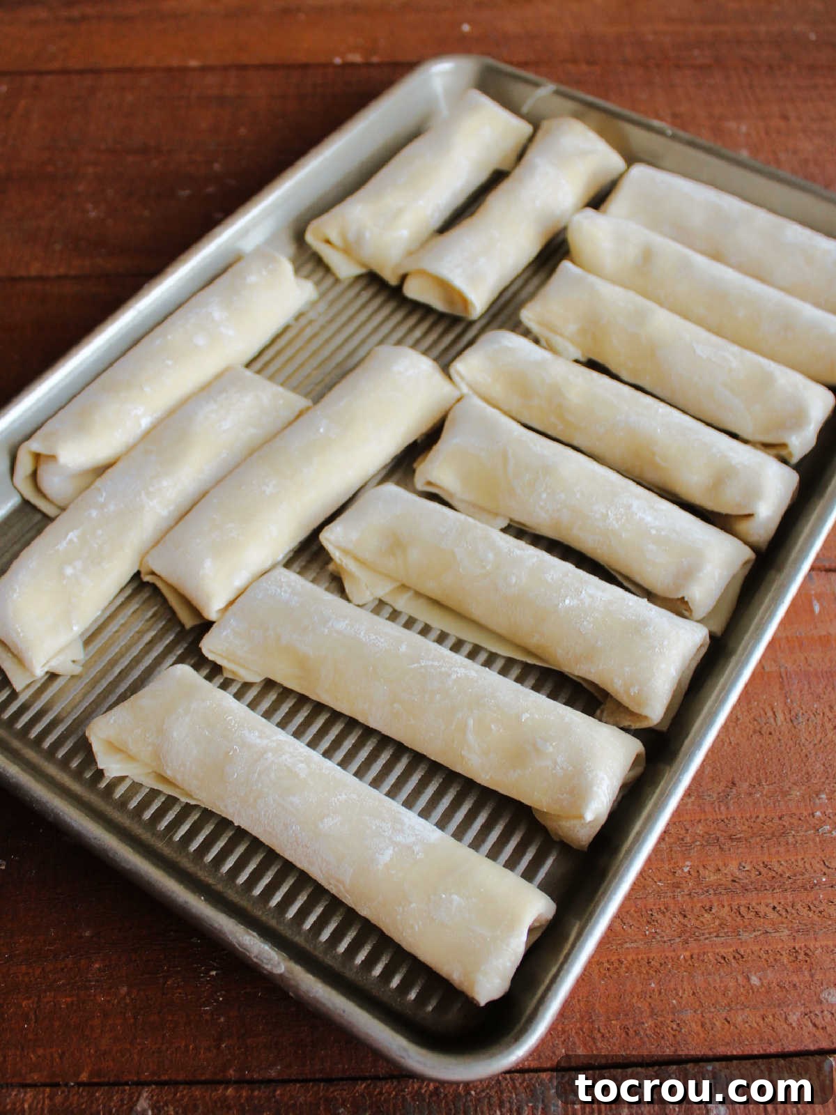 Egg Rolls Ready for Baking Tray of perfectly rolled crab rangoon egg rolls, lightly sprayed with cooking oil, and ready to be placed into the oven for baking.