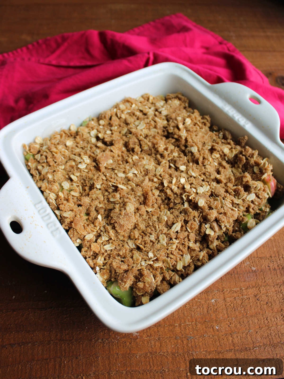 Brown sugar oat topping over rhubarb filling in square pan, ready to go in the oven. 