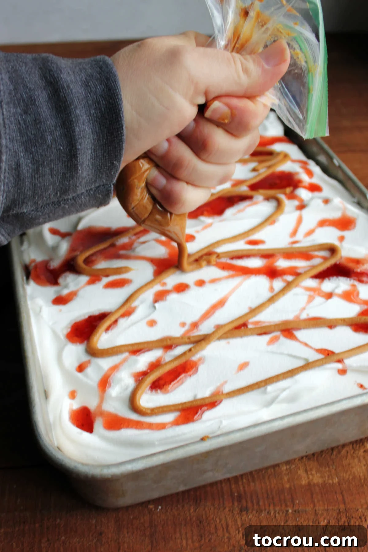 Decorative Drizzle of Peanut Butter and Jelly A final artistic drizzle of warm peanut butter and complementary jelly being applied over the freshly frosted poke cake, enhancing both its visual appeal and flavor.