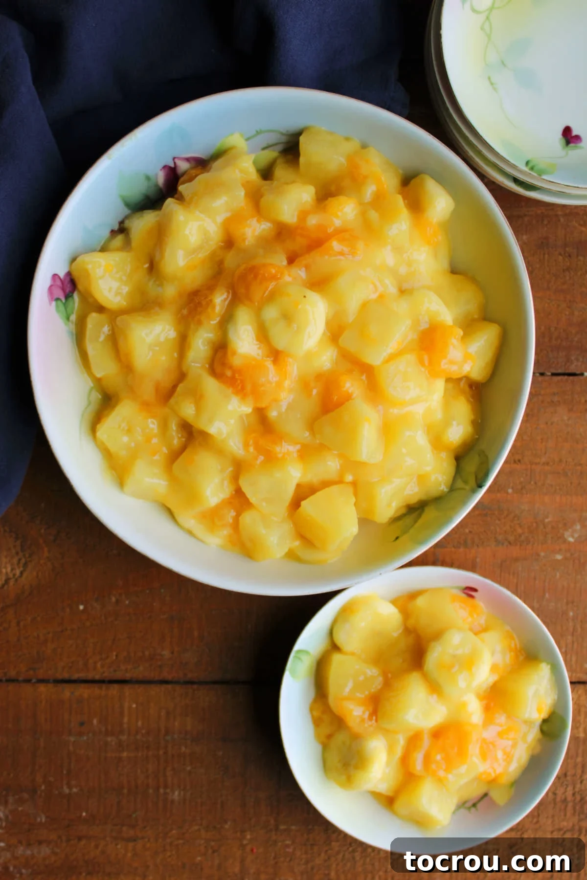 Looking down of vintage china bowl filled with sunshine fruit salad with a smaller bowl of fruit salad nearby.