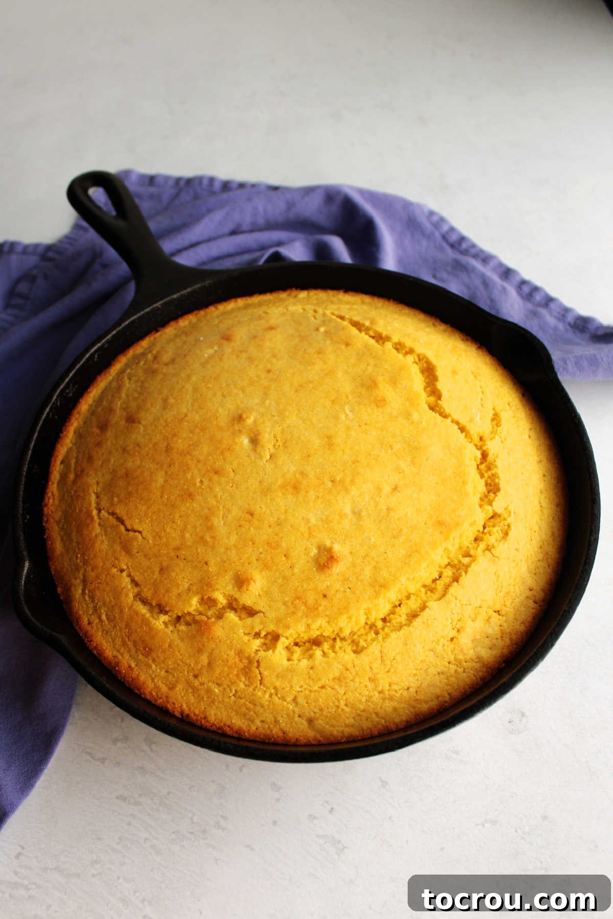 Golden yellow cornbread, piping hot and ready to serve, fresh from the oven in a cast iron skillet. Cast iron skillet filled with yellow cornbread straight from the oven.