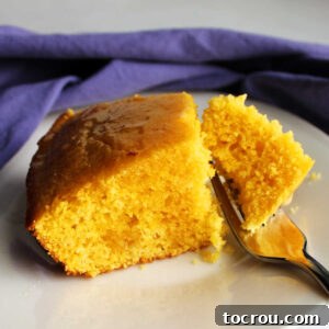 Fork getting a bite of skillet cornbread topped with butter and honey.