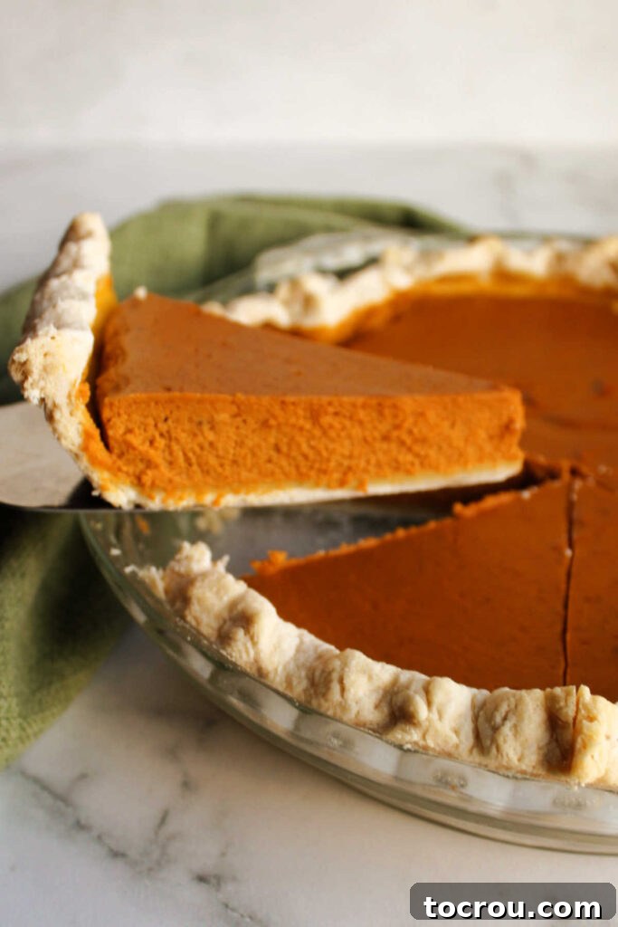 Lifting the first golden slice of maple pumpkin pie from the pan, ready to be served.