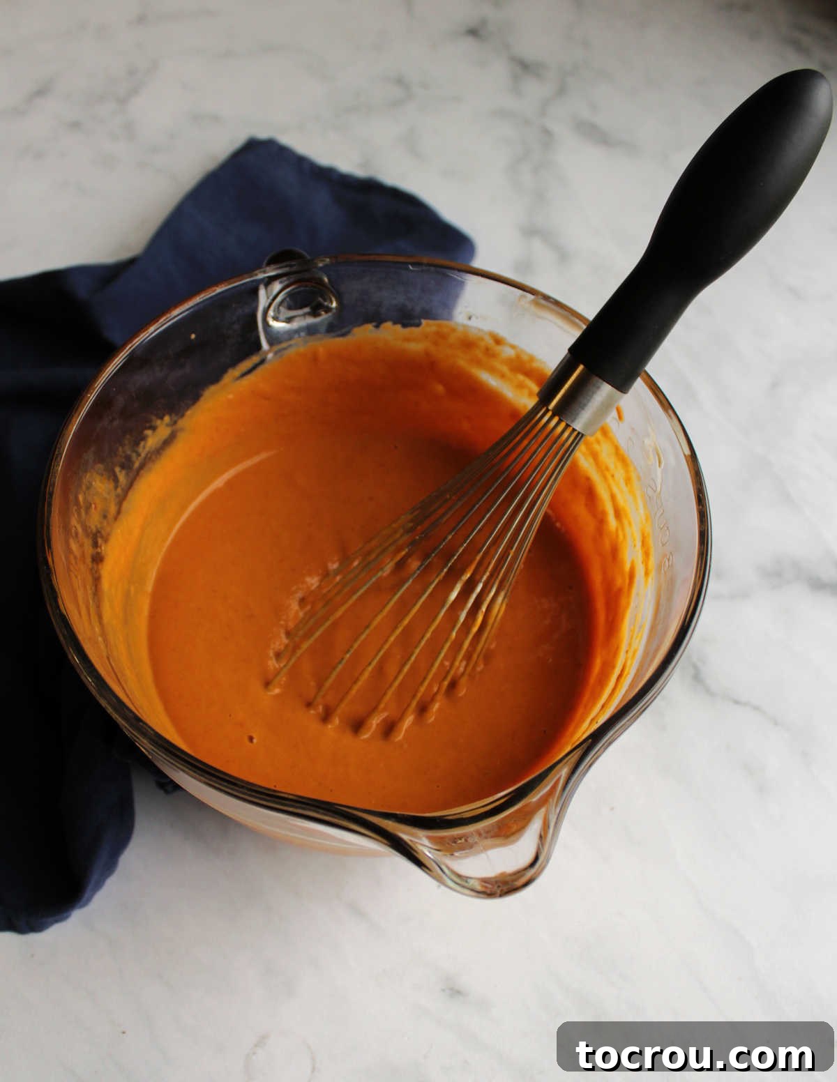 A mixing bowl brimming with smooth, golden maple pumpkin pie filling, ready to be poured into the crust.