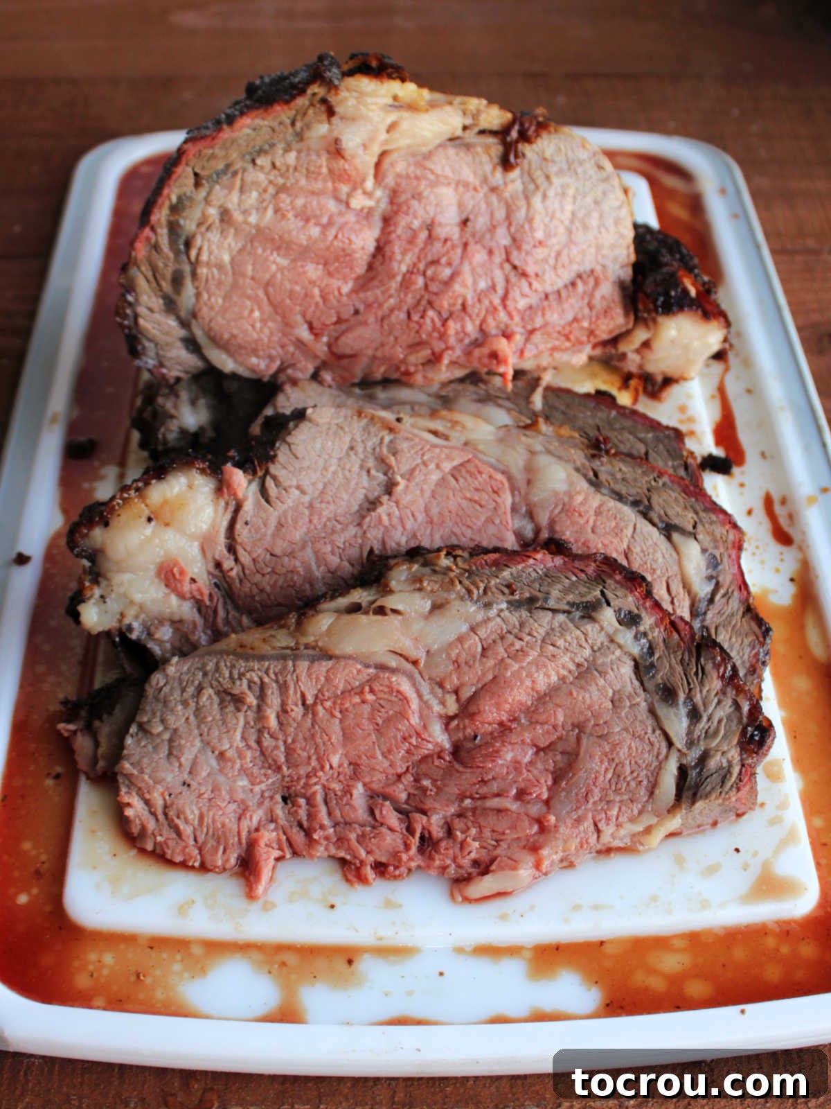 Cutting board filled with slices of medium rare prime rib, ready to be served.