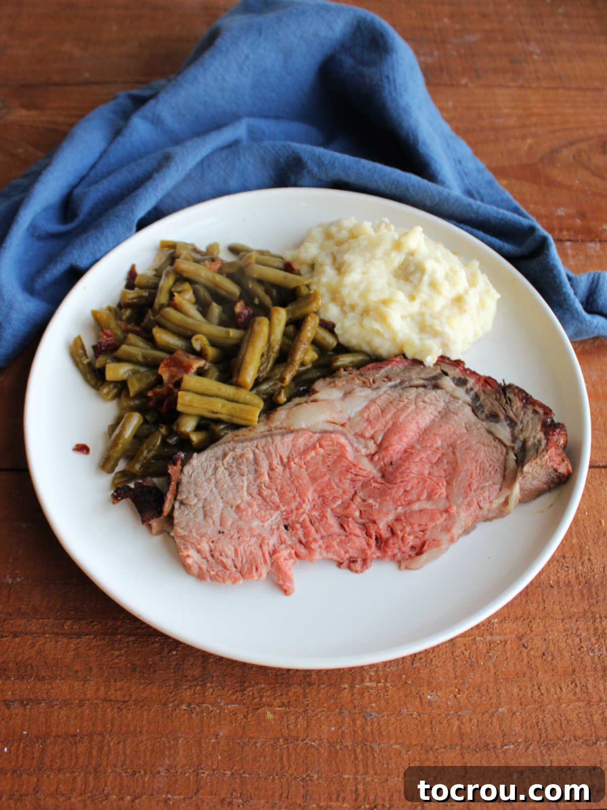 Dinner plate with prime rib, smothered green beans, and mashed potatoes, ready to eat.