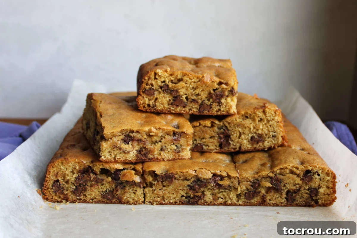 Perfectly cut squares of sourdough chocolate chip cookie bars arranged on a parchment-lined cutting board, ready for serving.