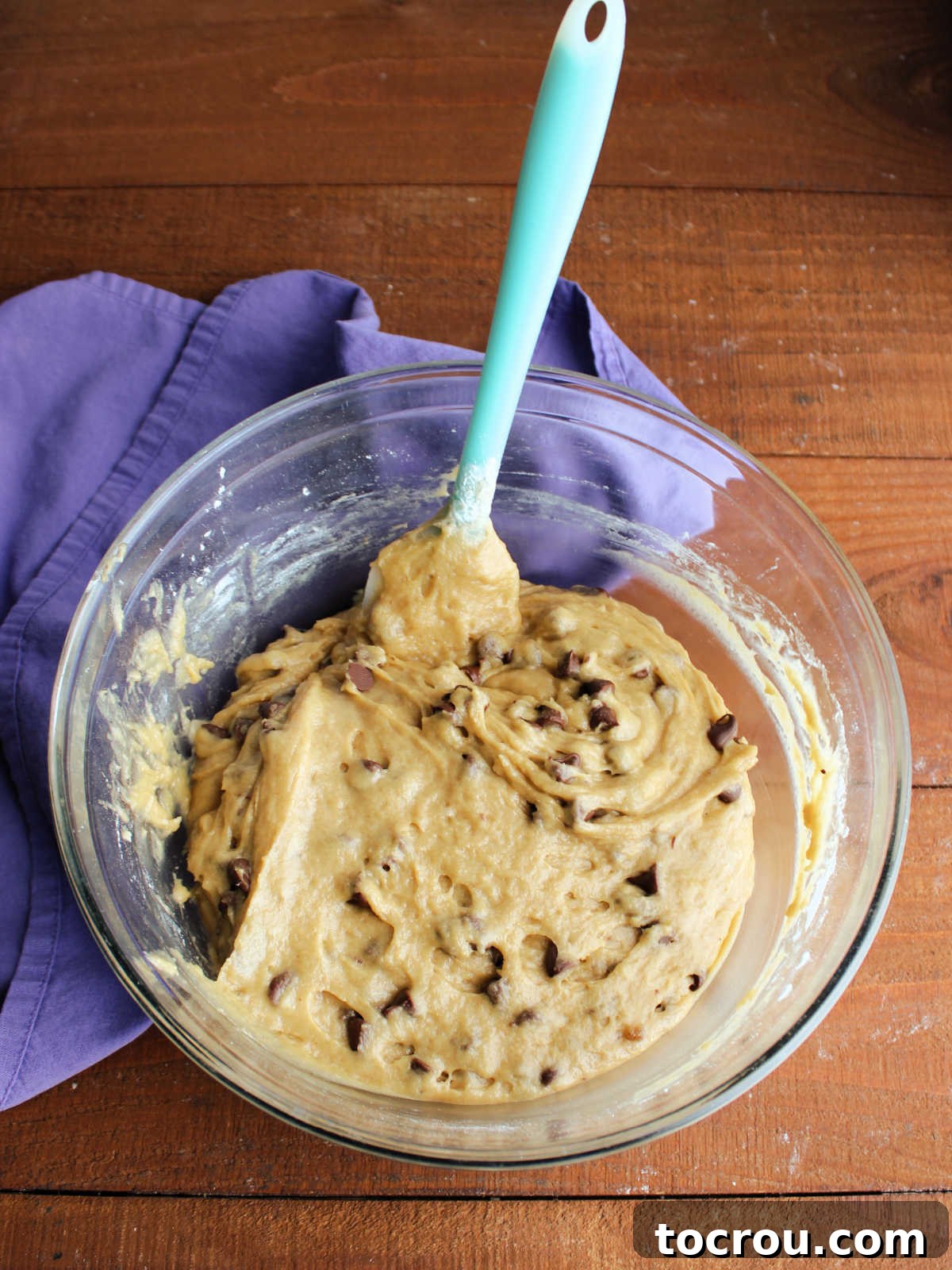 A mixing bowl filled with thick, rich sourdough chocolate chip cookie dough, perfectly mixed and ready to be pressed into the baking pan.