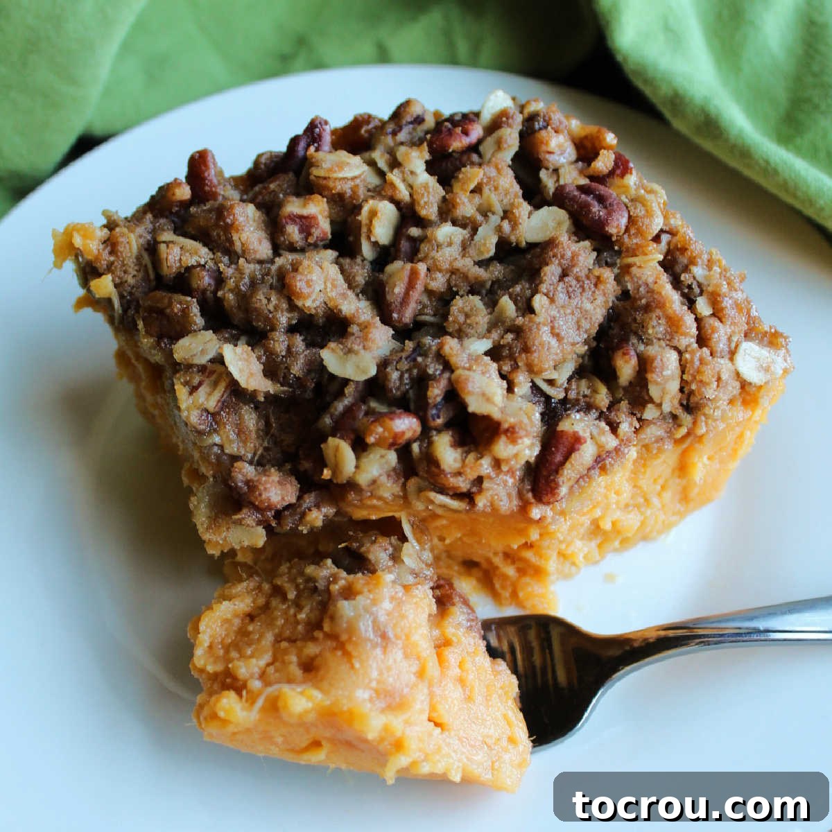 Forkful of maple sweet potato casserole topped with oats, pecans and brown sugar ready to eat.