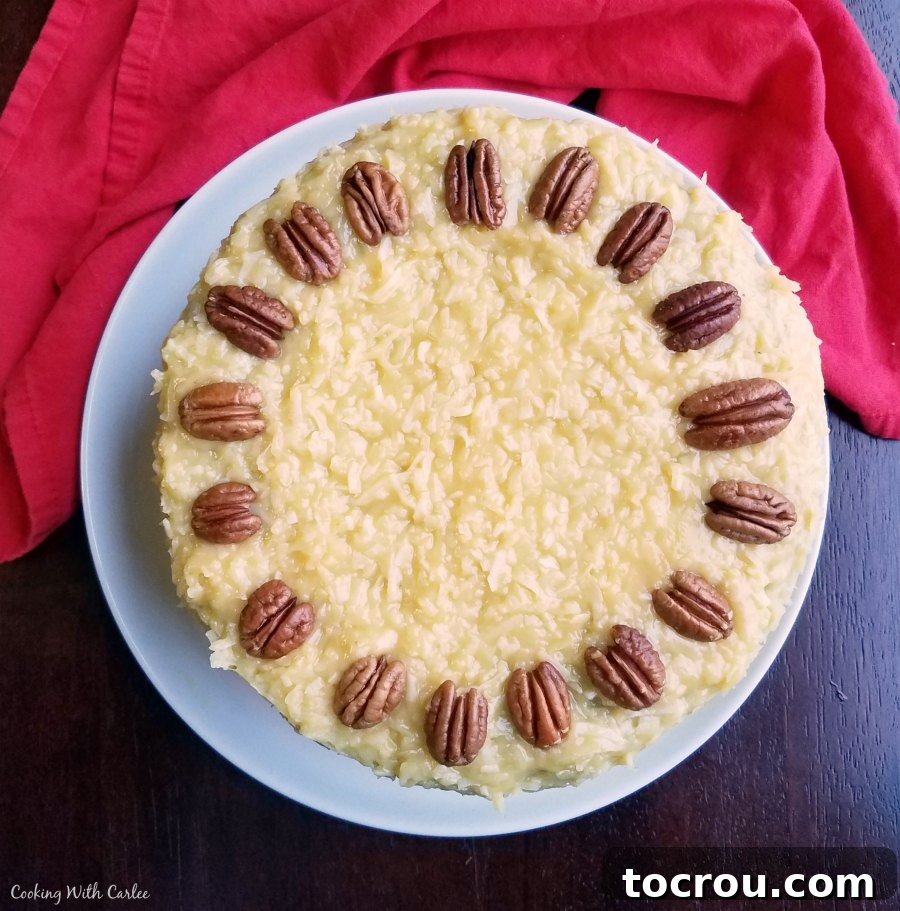 German Chocolate Cake with its signature coconut-pecan frosting and decorative pecan topping. Close-up top view of a German Chocolate Cake generously covered with thick coconut-pecan frosting and artfully placed pecan halves.