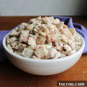 White serving bowl filled with white chocolate puppy chow with funfetti cake mix and extra sprinkles for coating.