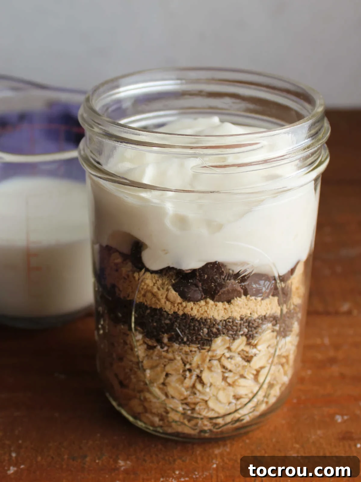 Ingredients layered in pint jar with measuring cup of milk in the background. 