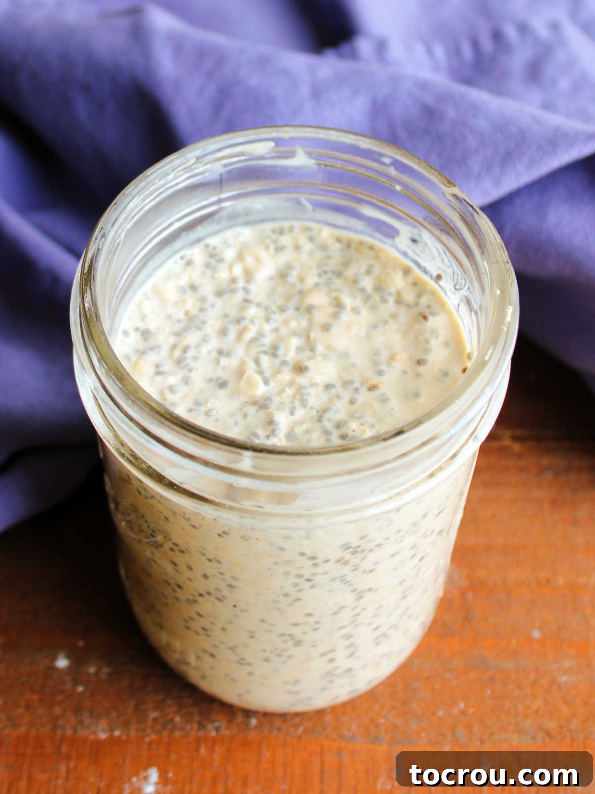 Jar of peanut butter overnight oatmeal after the liquid as been absorbed and the chia seeds and oats have expanded showing creamy thick texture. 