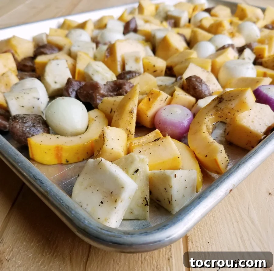 chopped vegetables coated in seasoning and spread over baking tray ready to go in oven to roast.