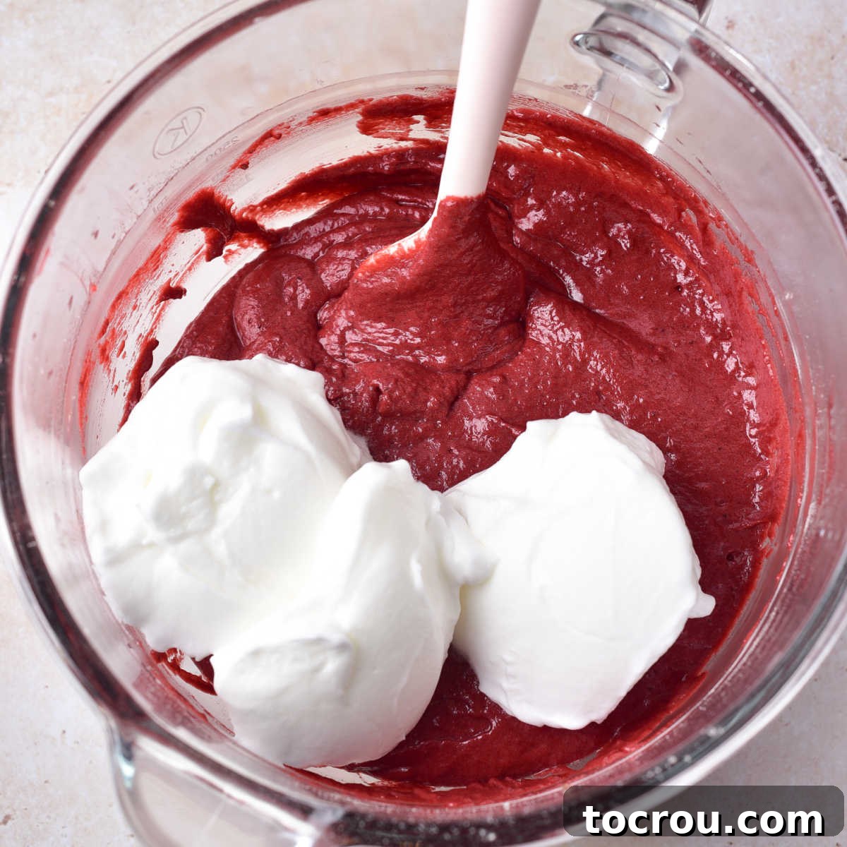 Gently Folding Egg Whites into Red Velvet Batter Folding whipped egg whites into red velvet cake batter mixture.