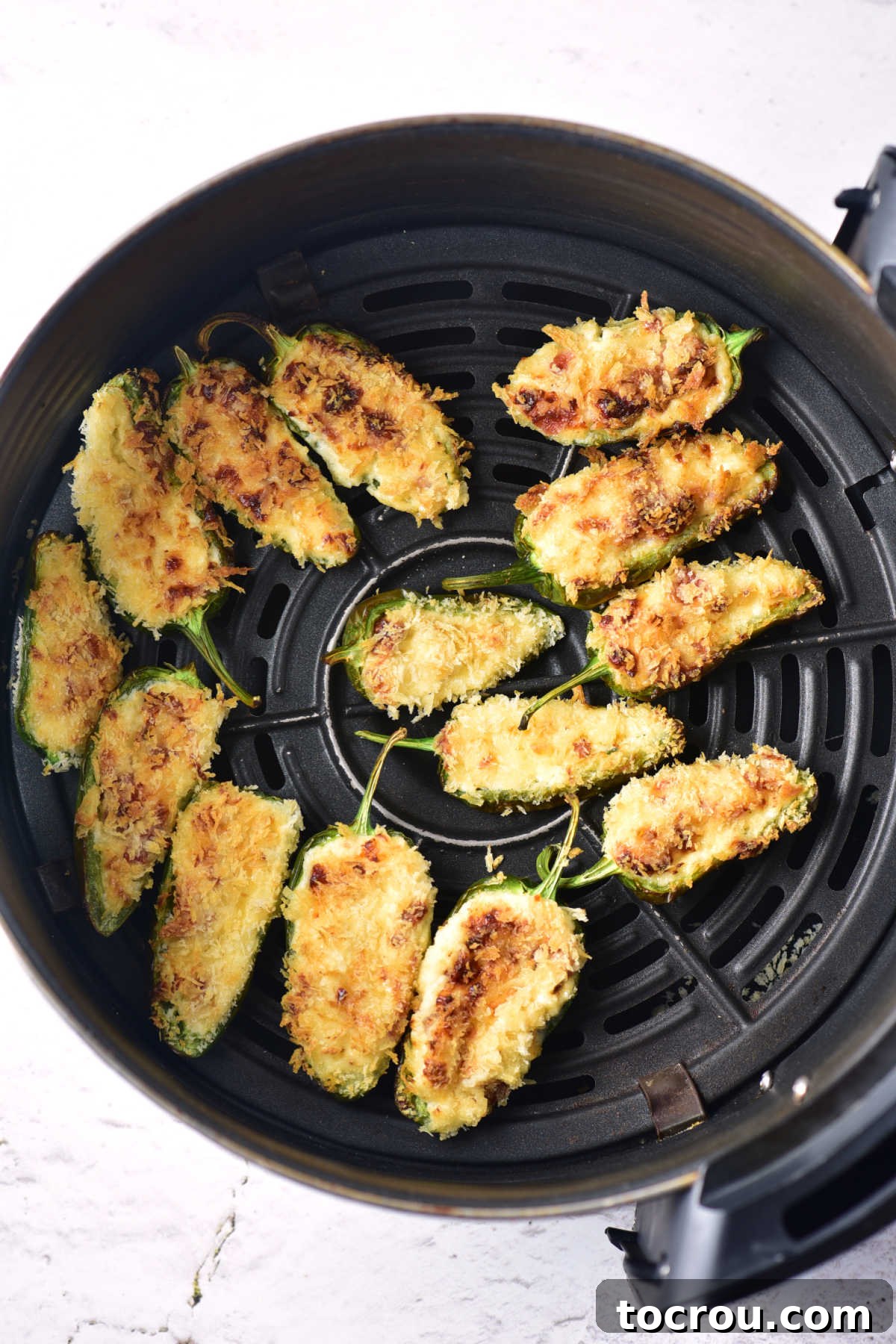Perfectly Cooked Air Fried Jalapeno Poppers Air fryer of cooked jalapeno poppers with golden brown panko topping, ready to serve.