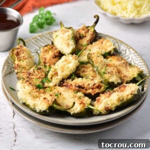 Air Fryer Jalapeno Poppers Recipe Image Plate of stuffed jalapenos with cream cheese, cheddar, and bacon filling and golden bread crumbs on top, ready to eat.