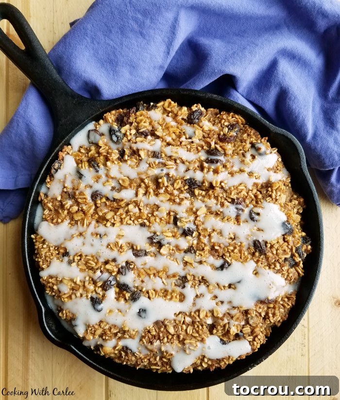 A cast iron skillet brimming with freshly baked oatmeal, elegantly drizzled with a sweet glaze, promising a comforting start to the day.