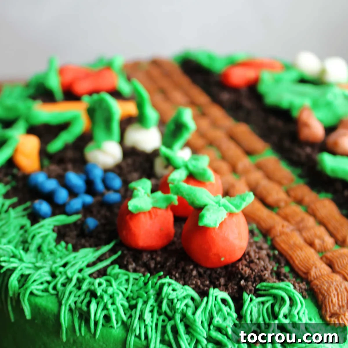 Vibrant Modeling Chocolate Vegetables Decorating a Cake Close up of veggies made from white modeling chocolate dyed different colors and shaped then placed on top of a cake.