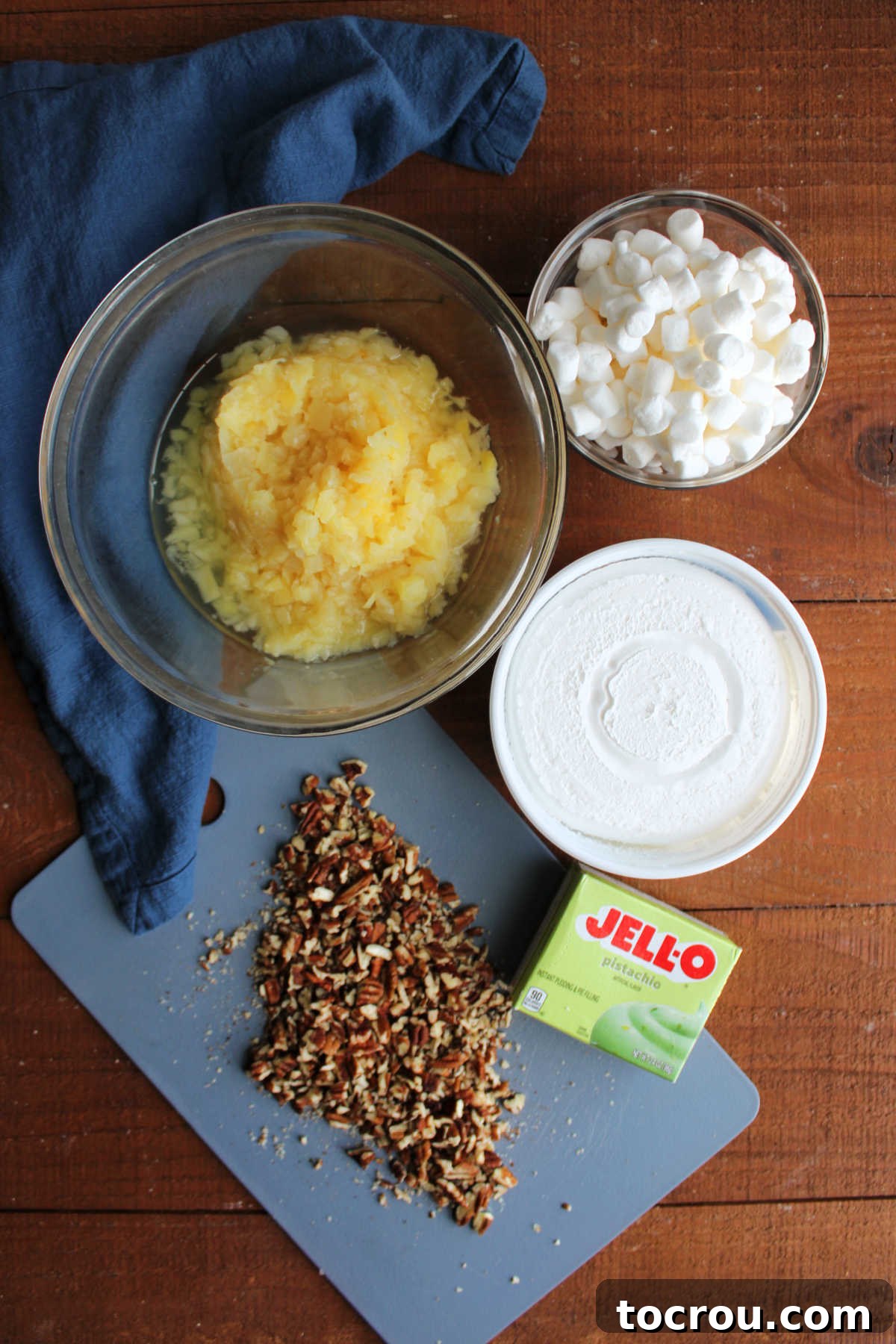 Ingredients including pistachio pudding mix, crushed pineapple, chopped pecans, mini marshmallows and cool whip. 