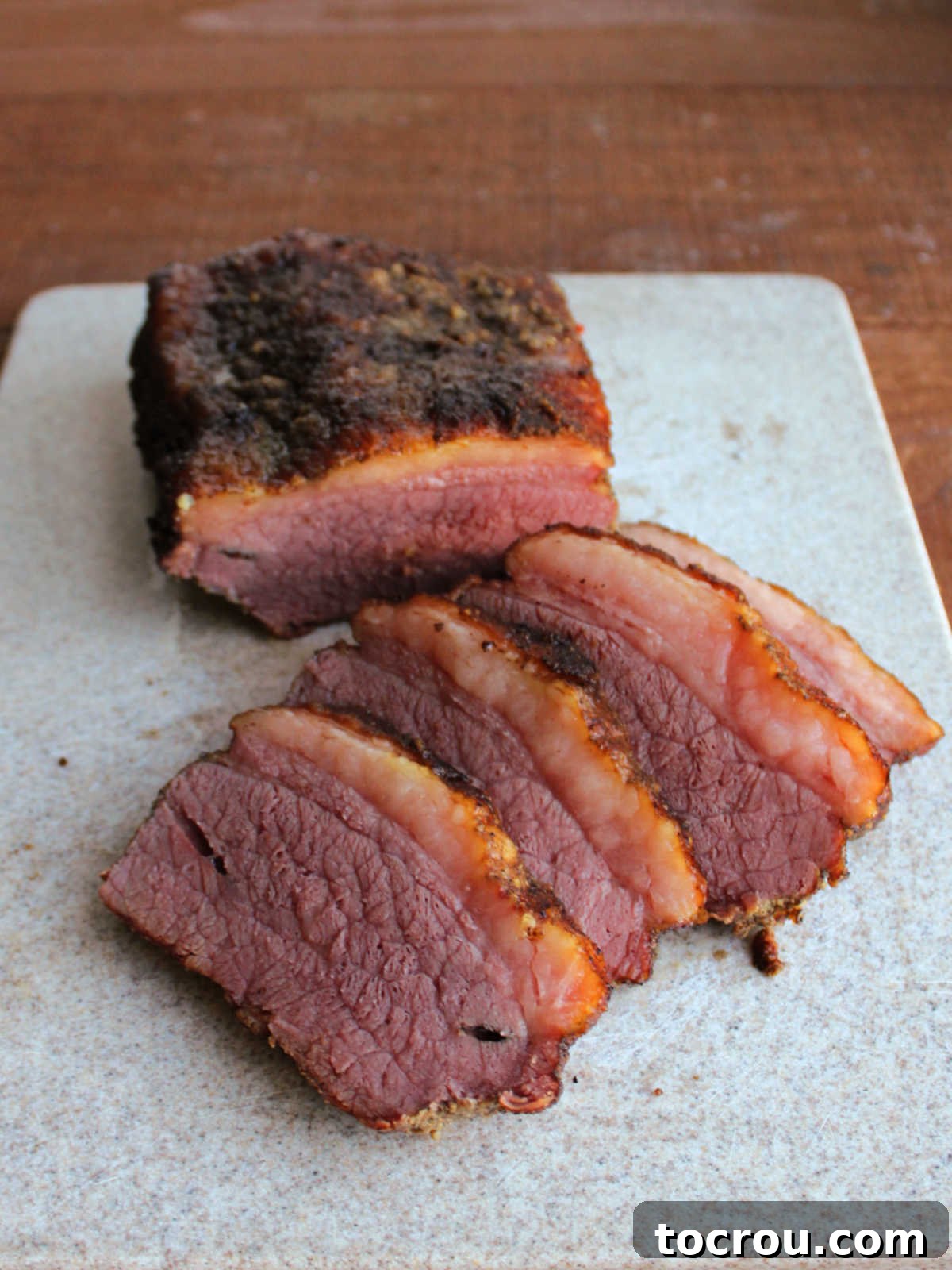 Unforgettable Pellet Smoked Corned Beef 3 Perfectly sliced smoked corned beef brisket displayed on a wooden cutting board, ready to serve.